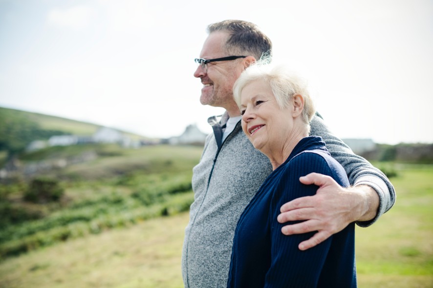 Départ à la retraite Un couple de retraités se donnant l'accolade, en pleine nature, le regard au loin, heureux.
