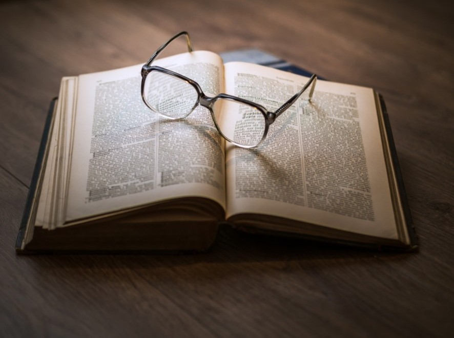L’importance de la lecture Des lunettes de vue posées sur un livre ouvert sur une table en bois.